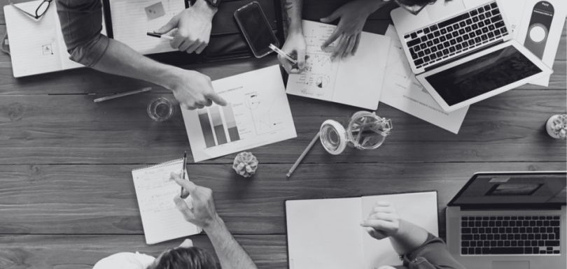 Imagen cenital de varias personas trabajando en una mesa con papeles, desarrollando una estrategia de crecimiento empresarial